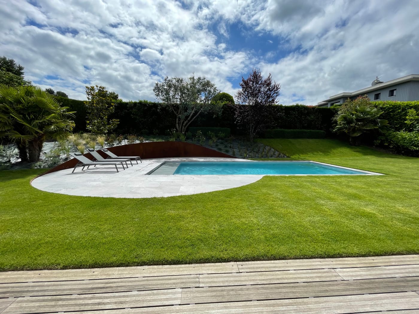 Piscine traditionnelle, pierre grise et acier corten