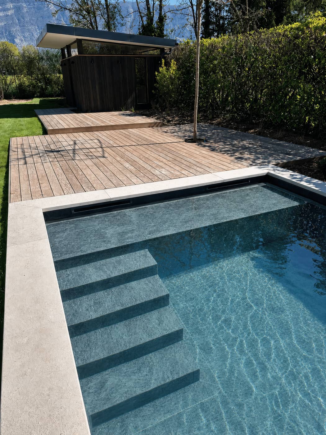 Piscine traditionnelle, pierre claire et bois exotique