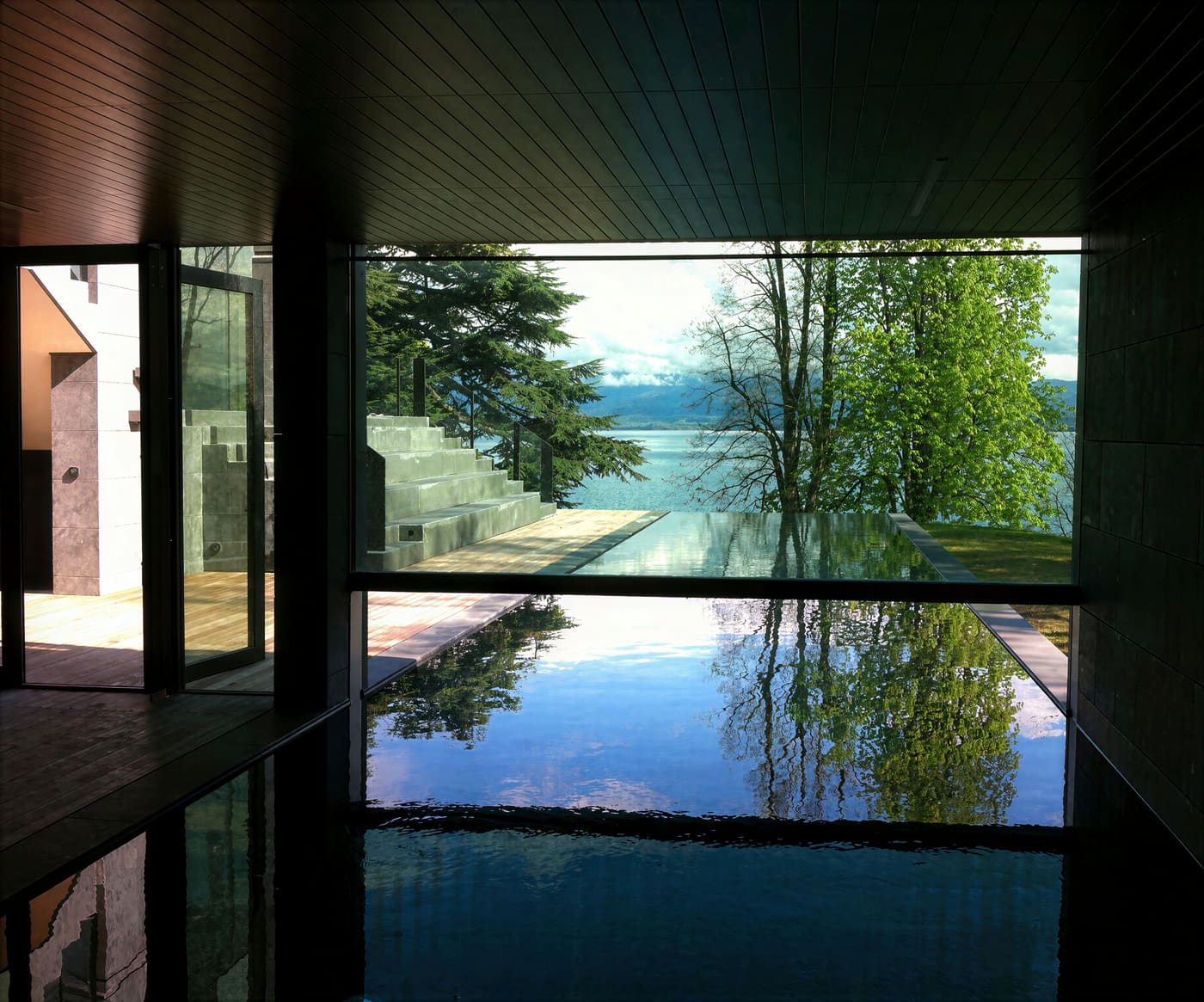 Piscine à débordement, pierre grise et mosaïque sombre